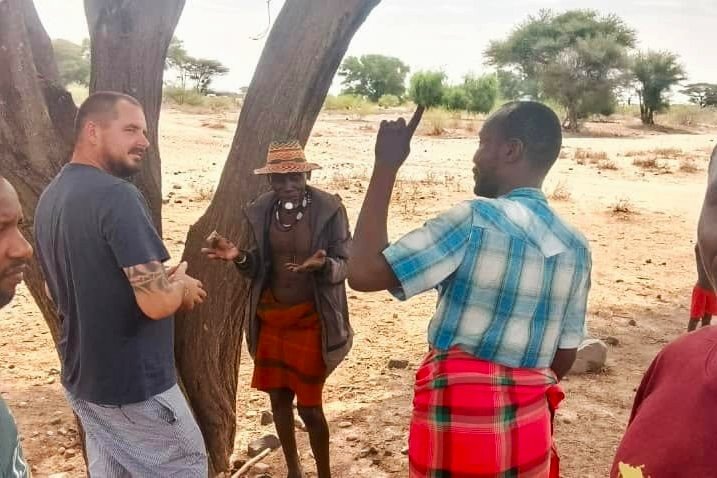 Seth in conversation with elders under an acacia tree