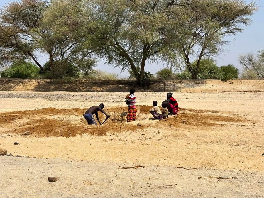 A family digging for water in a dry riverbed
